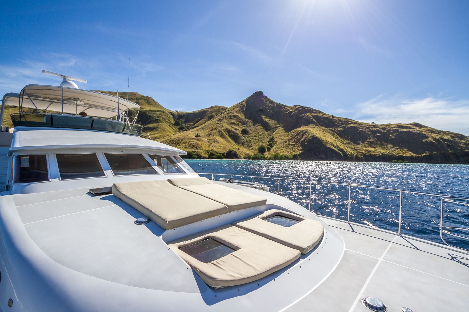 From the foredeck: dry golden hills over sparkling water — the island end of the crossing