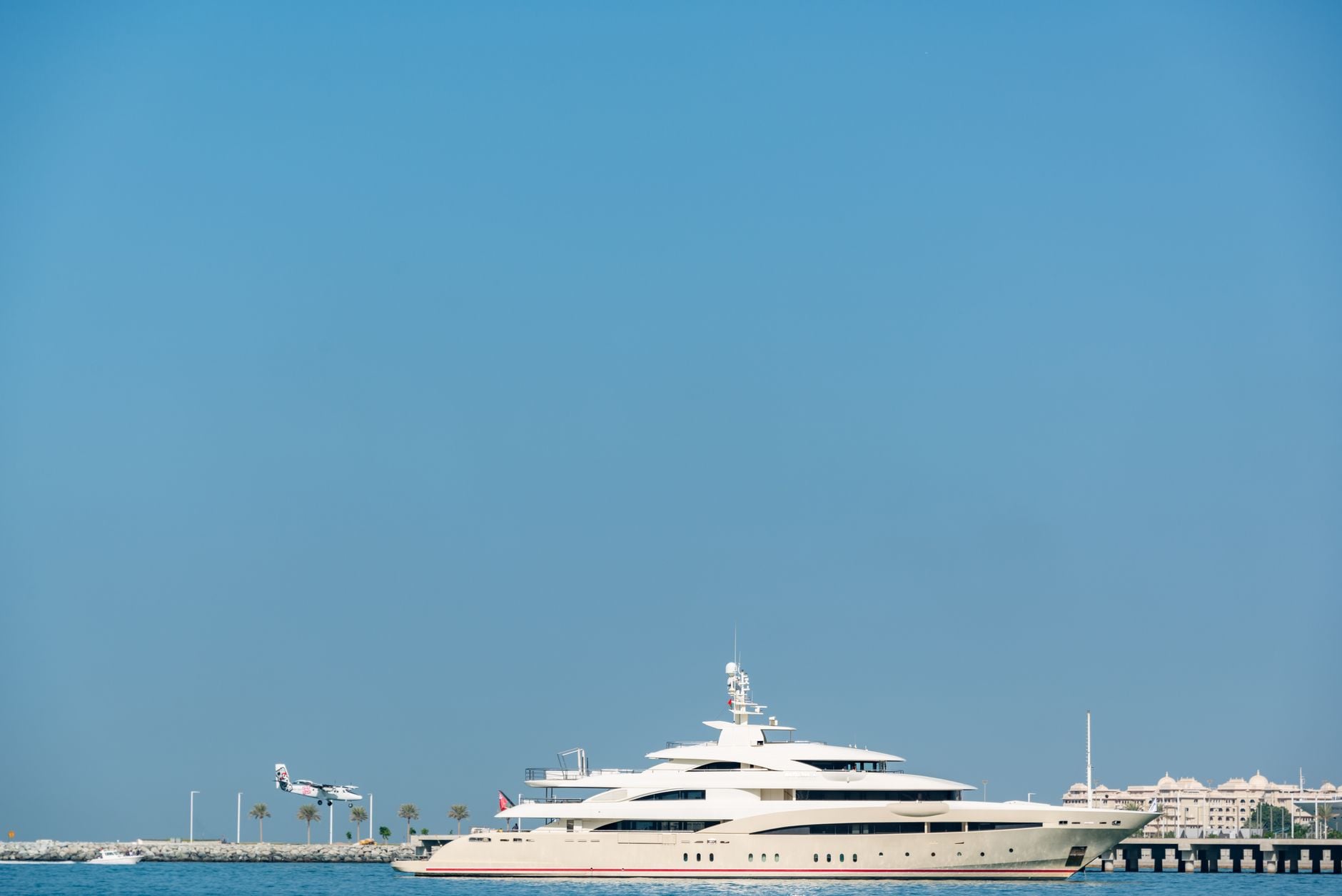 The neighbors at the moorings — a cream superyacht against hard blue sky