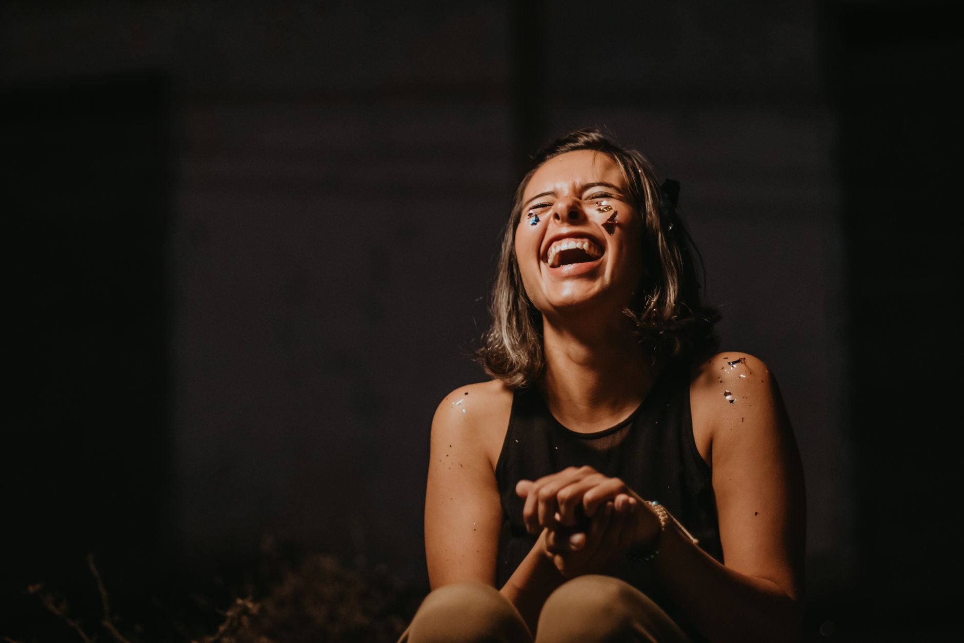A person laughing, photographed against a dark background