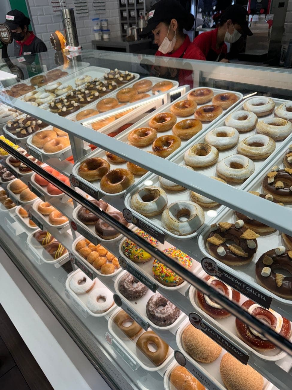 A donut shop display case, trays of glazed and iced donuts