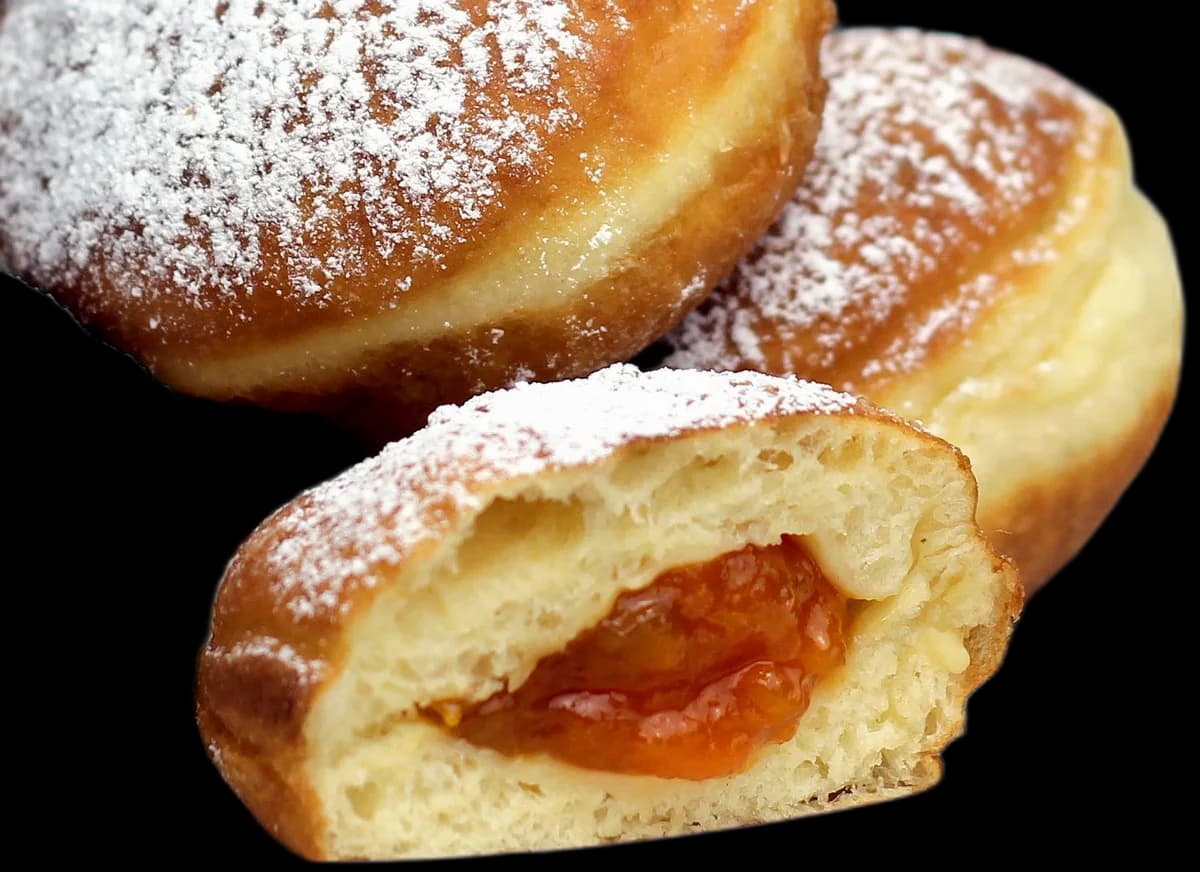 A sugared jam donut cut open to the apricot filling