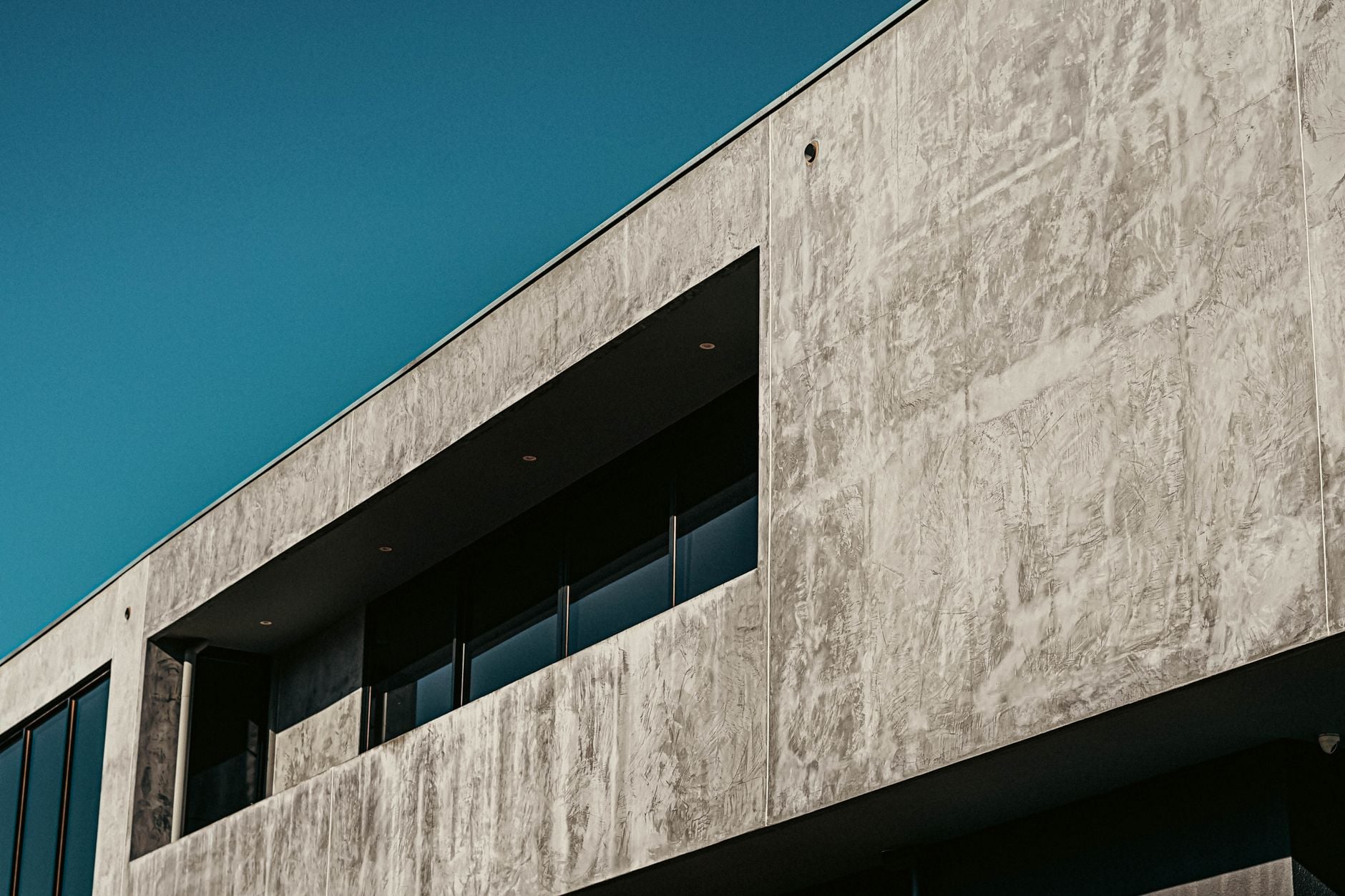 Board-marked concrete facade against a teal evening sky