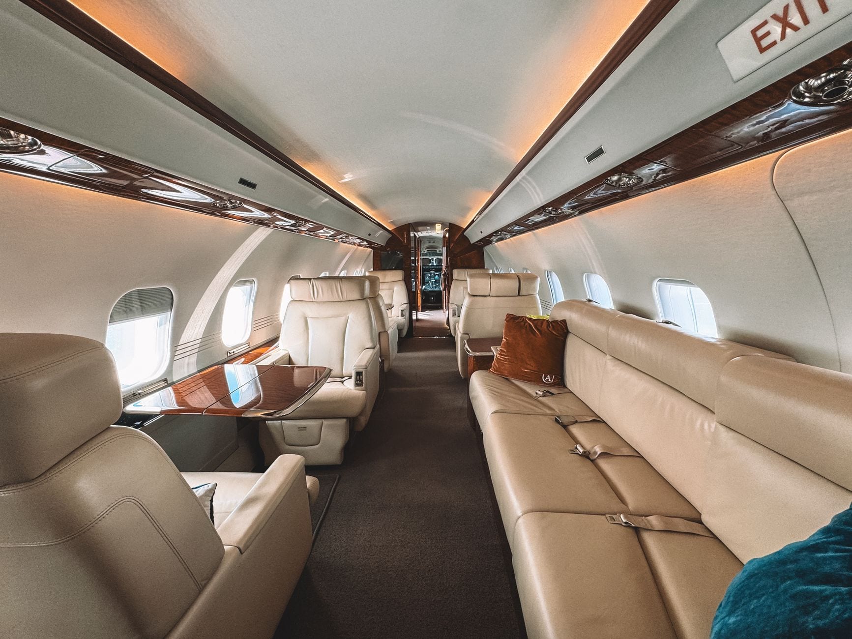 A business-jet cabin looking aft, seats in cream leather