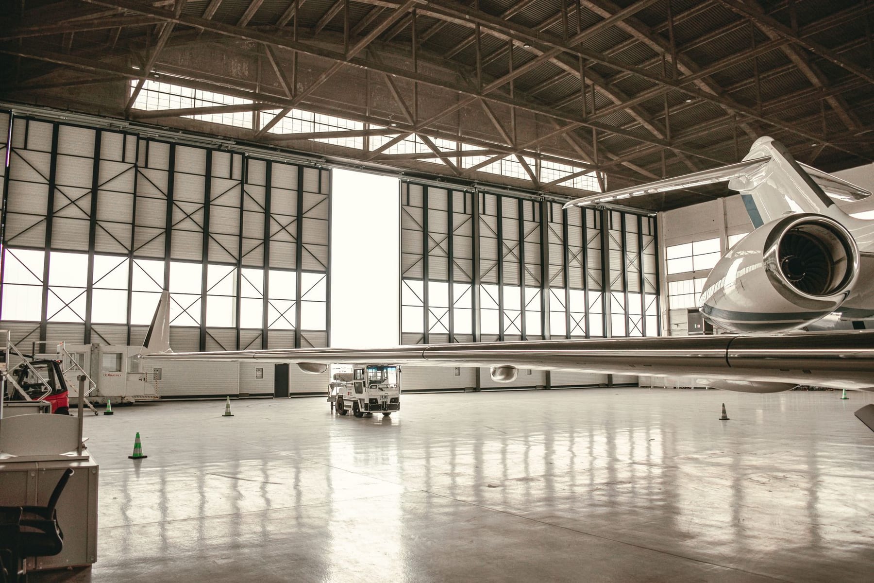 A midsize business jet in a hangar, doors open to the light