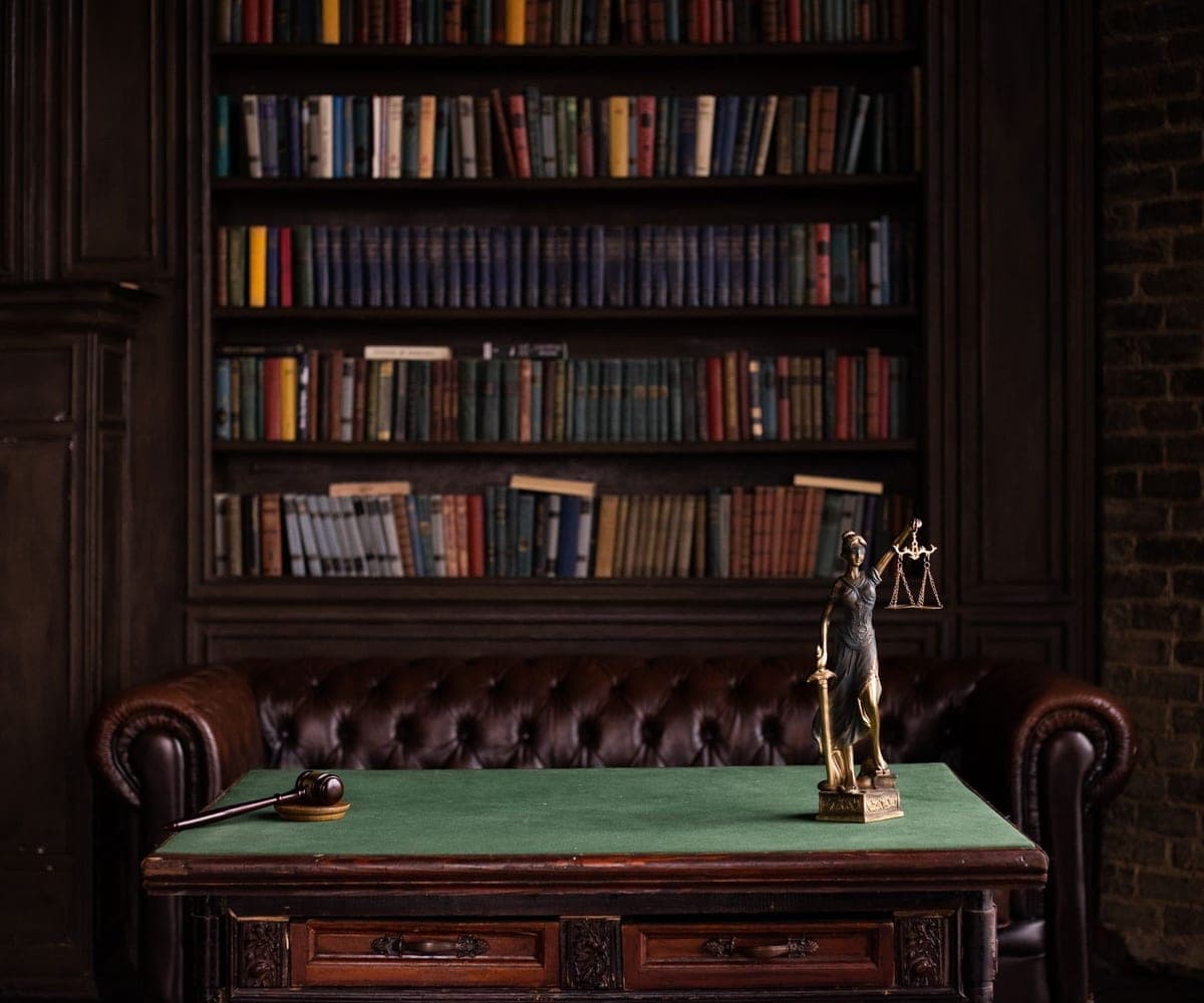 A law library with a small brass figure of Justice on a writing desk