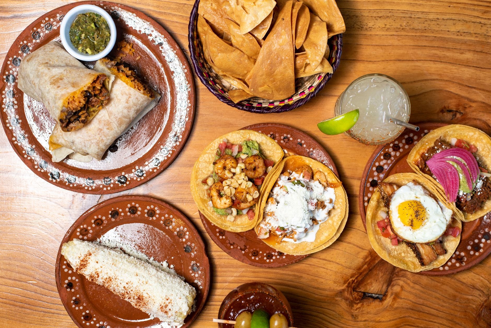 The table at Relleno: a split burrito, elote, tacos, chips and aguas frescas