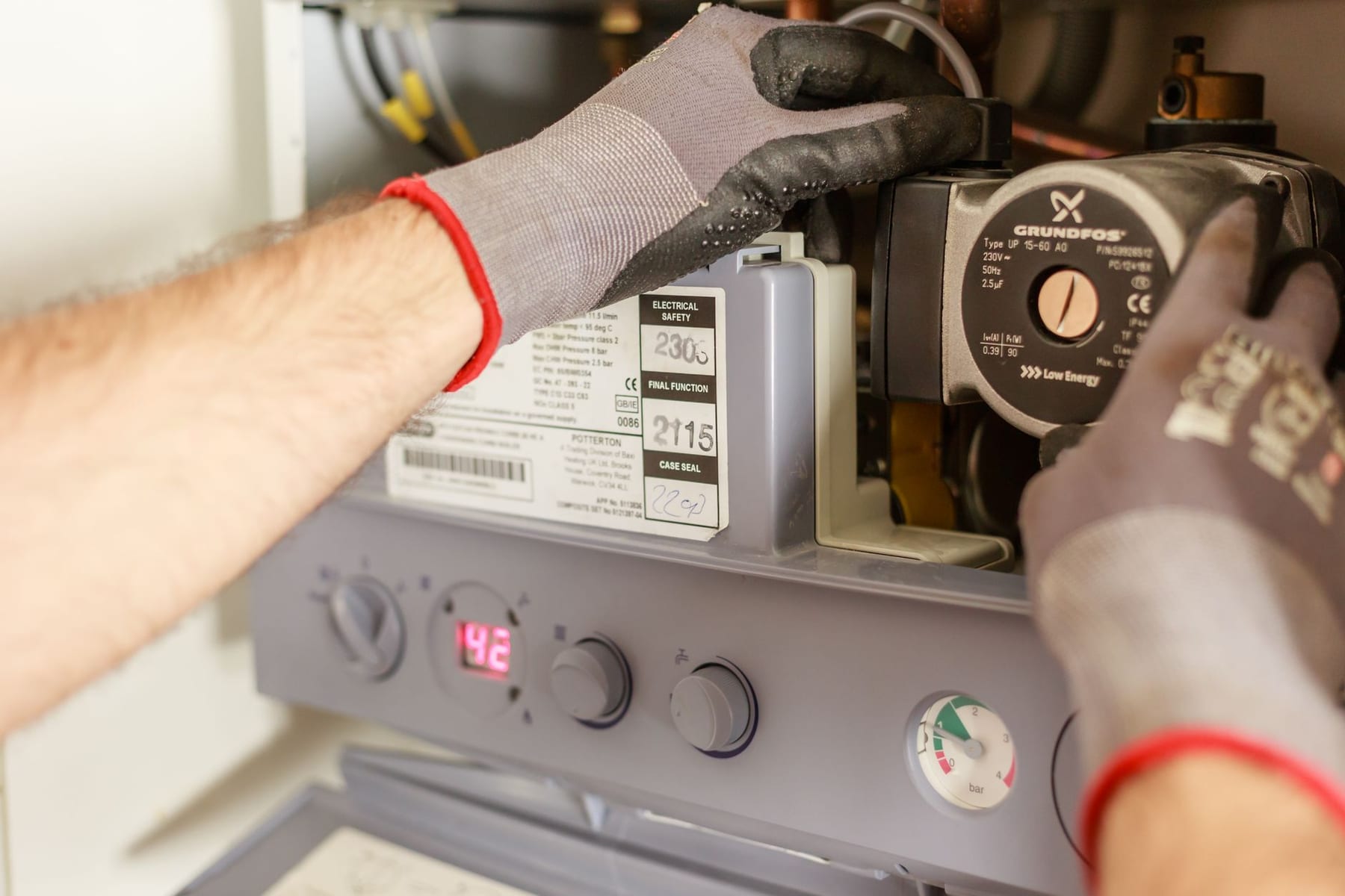 Gloved hands adjusting the control panel on a heating unit