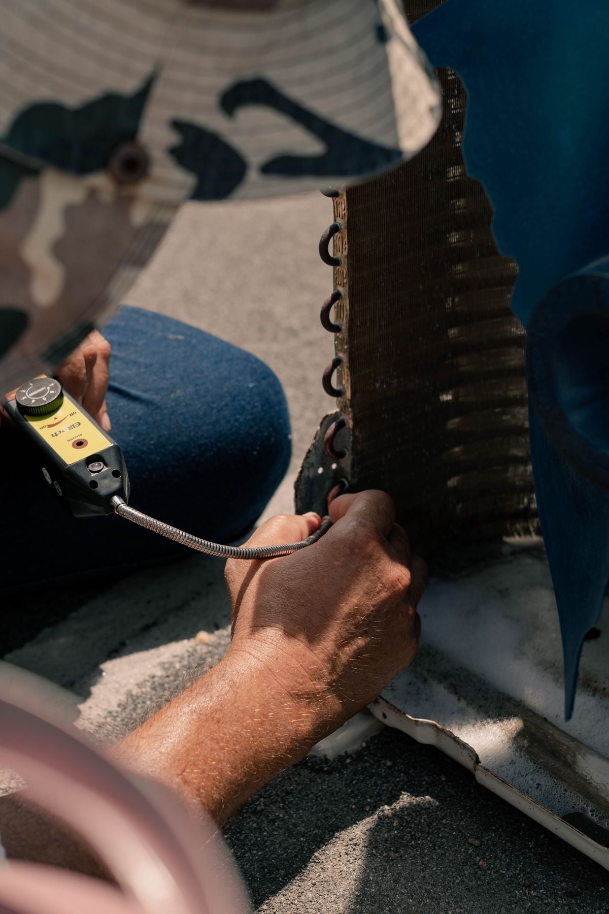 A leak detector probe held against a condenser coil