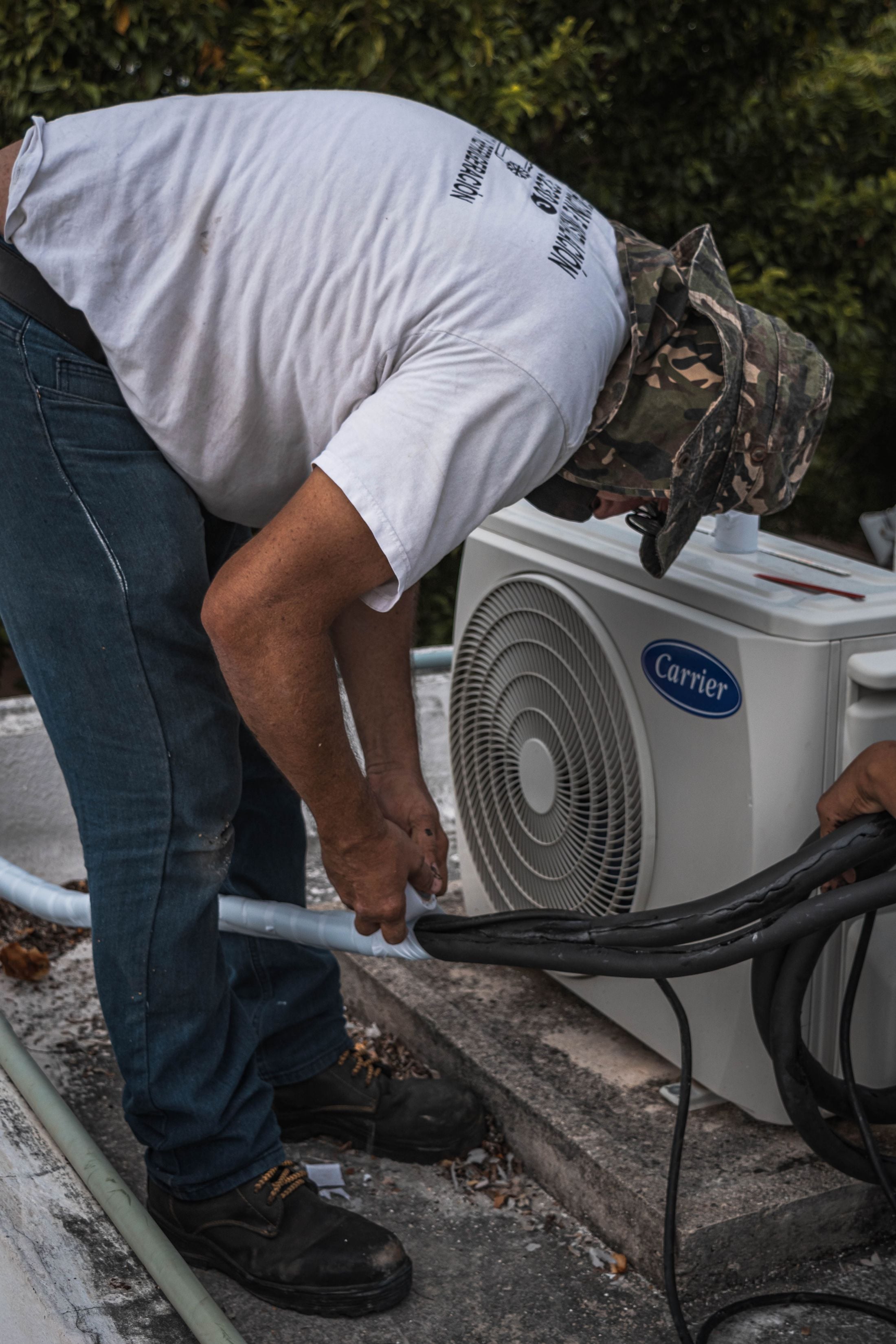 A technician working the line set on a Carrier condenser